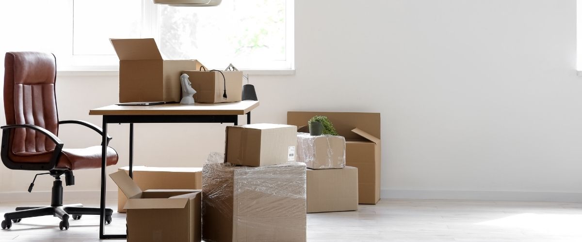 Un bureau encombré de cartons et une chaise.