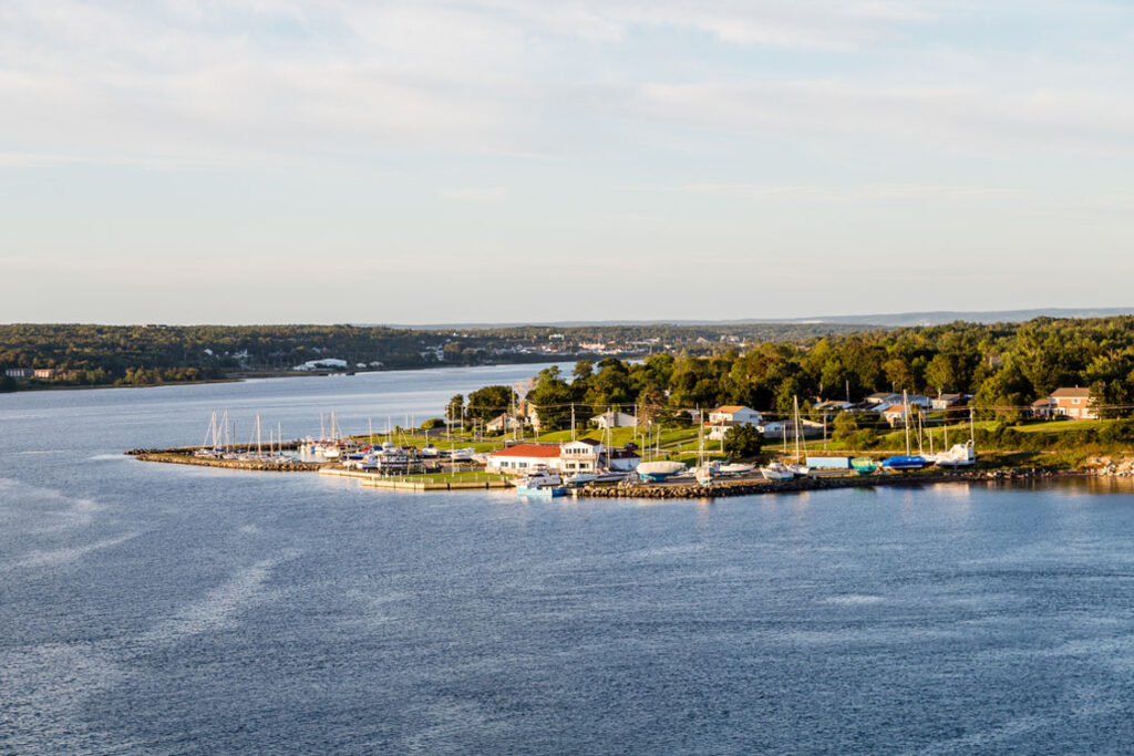Scenic marina in Sydney, Nova Scotia with sailboats and waterfront homes.