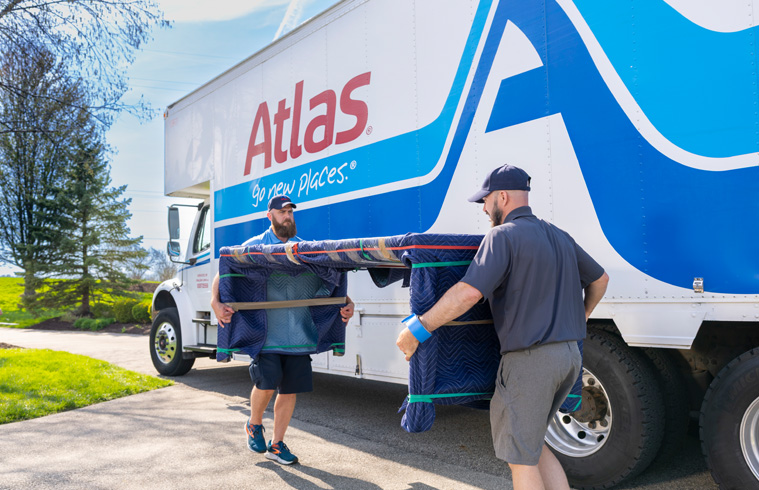 Atlas movers carry padded furniture during home relocation.