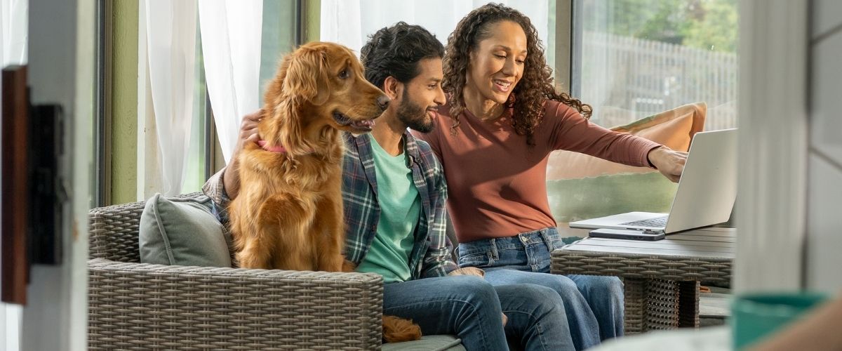 Un homme et une femme sont assis ensemble sur un canapé, un chien se reposant confortablement entre eux.