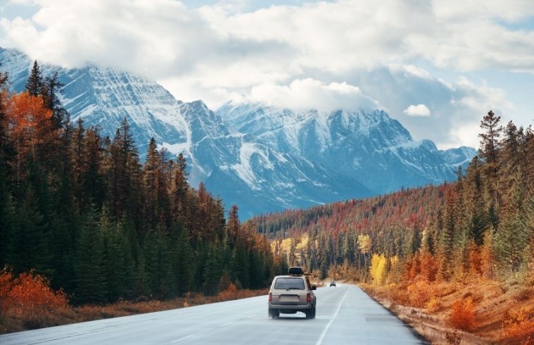 A car navigates a winding mountain road, surrounded by lush greenery and rocky cliffs.