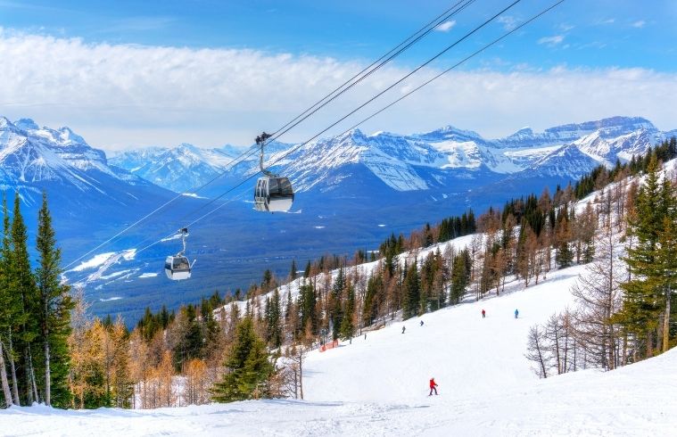A ski lift ascends a snow-covered mountain, surrounded by frosted trees under a clear blue sky.