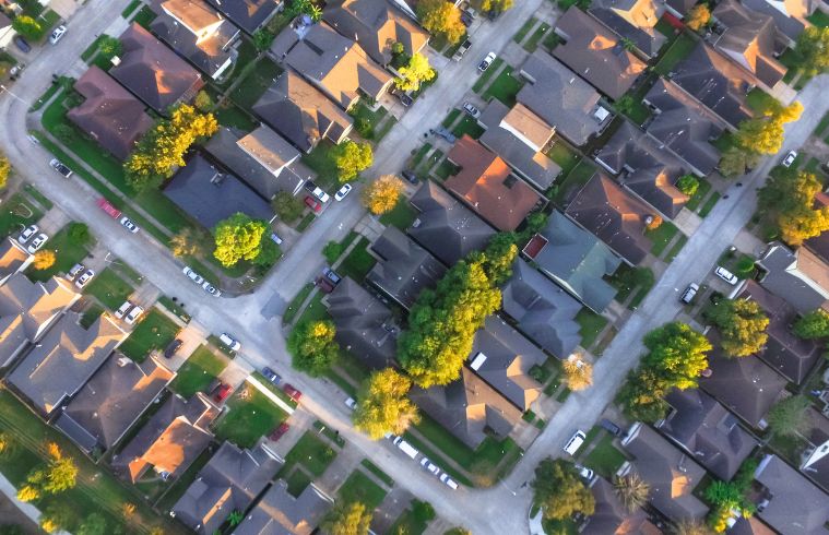 Vue aérienne d'un quartier résidentiel de banlieue comprenant de nombreuses maisons et des espaces verts.